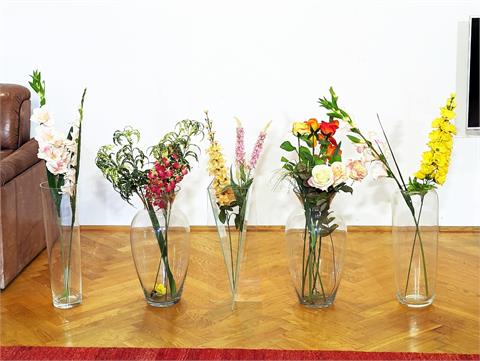 Fünf Glasvasen mit Kunstblumen